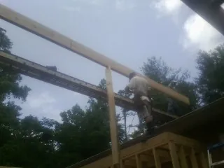 Carpenter setting a ridge beam over a new addition frame — Ice Dam Removal by Roofing Brothers in Hurt