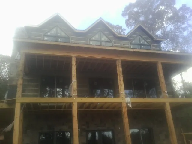 Dormers and porch framing on a large log home under construction — Roof Coating work by our crew in Hurt
