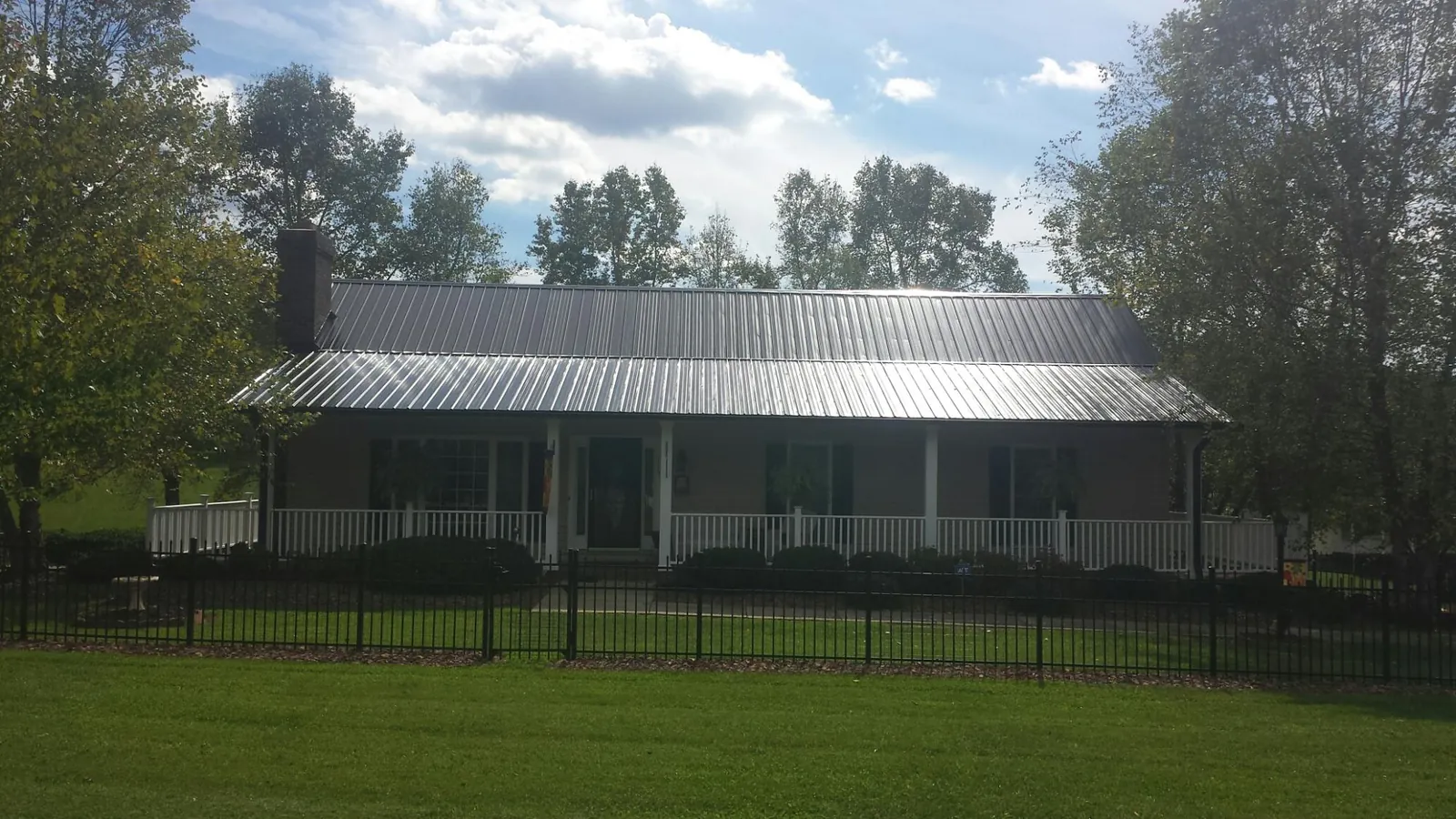 Gray metal roof on a brick ranch with a full width front porch — Gutter Guard Installation work by our crew in Hurt