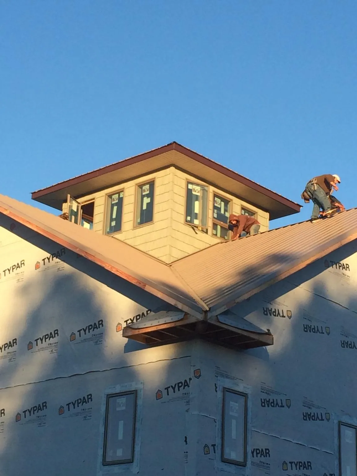 Roofers working around a rooftop cupola on a new metal roof at sunset — Roof Waterproofing in Hurt by Roofing Brothers